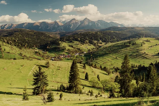 Patchwork fields on hillsides with mountains behind.