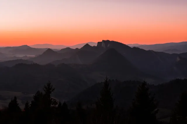 Dark mountain silhouettes beneath an orange sky.