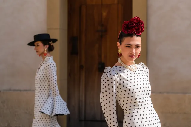 Two women in polka-dot dresses beside wooden doors.