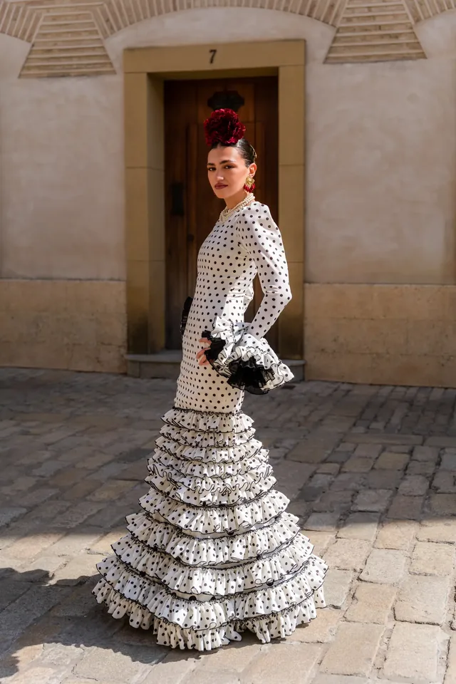 Woman in a polka-dot dress standing sideways outside a doorway.