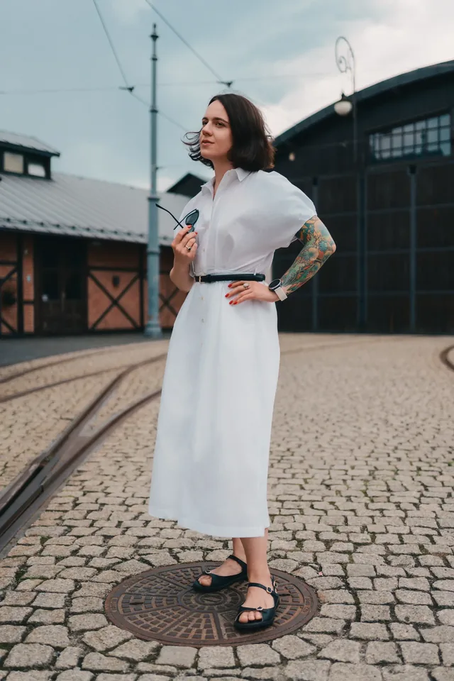 Full-length portrait of a woman in a white dress in a cobbled square.