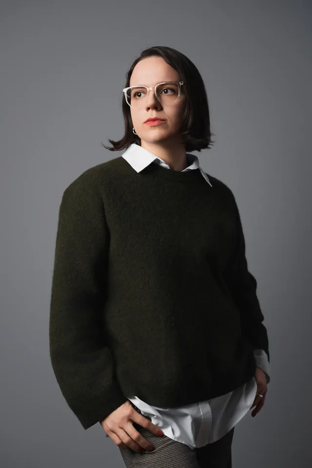 Studio portrait of a woman in a jumper with hands in front of her.