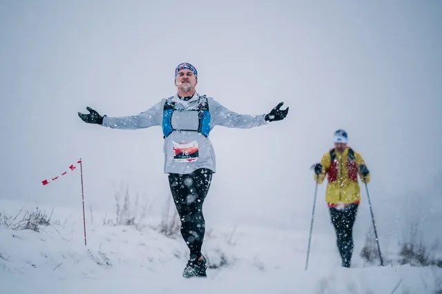 Runner with arms outstretched on a white slope.
