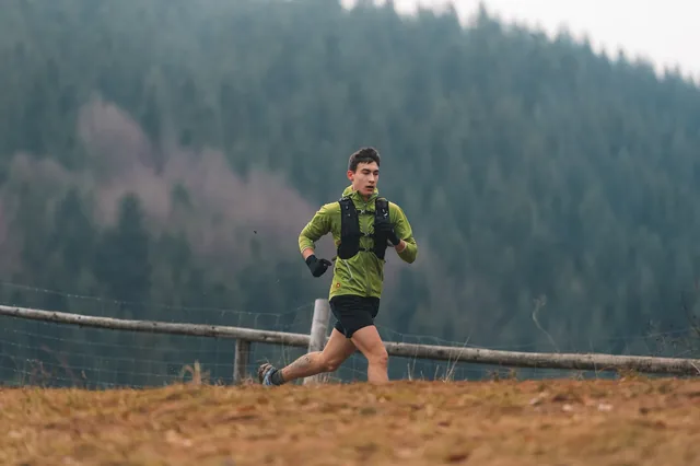 Runner in a green shirt beside a wooden fence.