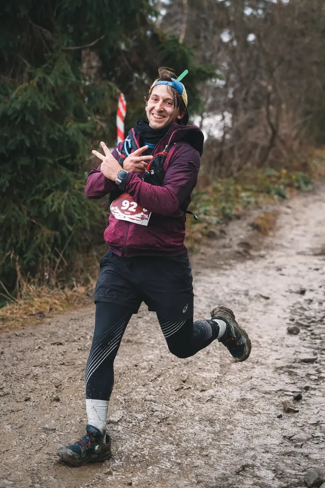 Runner making a hand gesture while running through a forest.