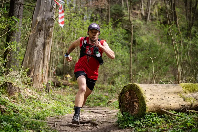 Runner in a red shirt beside a fallen log.