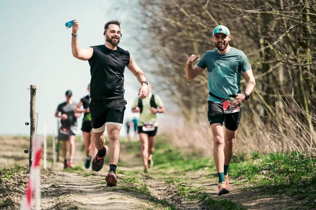 Two runners with raised hands on a marked course.