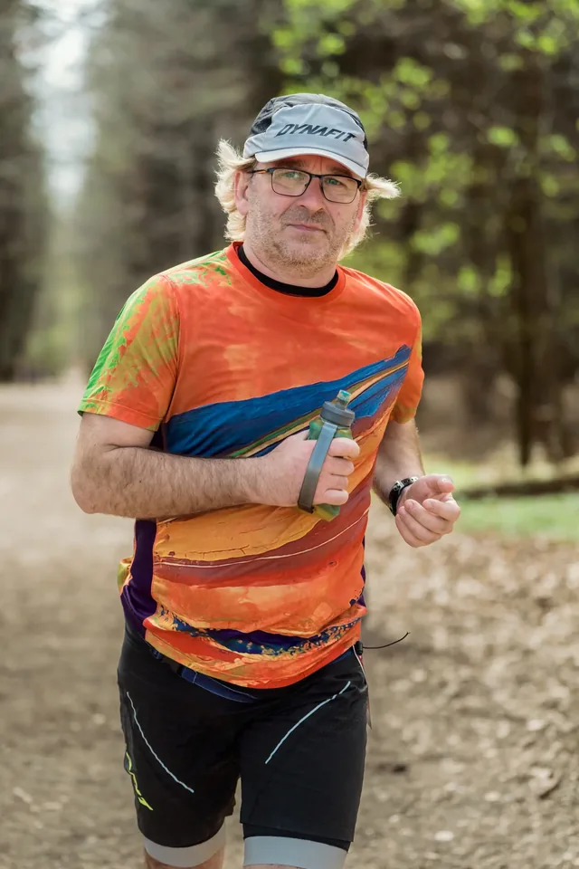 Runner in an orange shirt and pale cap.