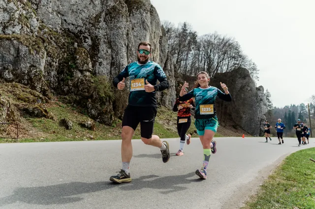 Group of runners on a paved course below cliffs.
