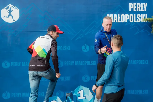 Participants talking beside a podium in front of a blue backdrop.