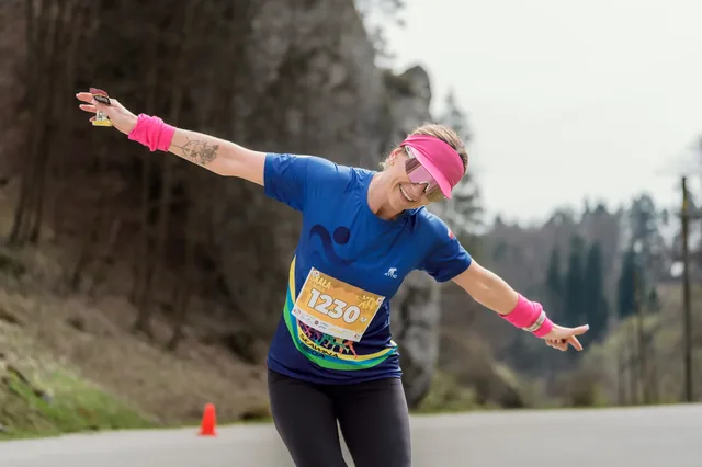 Runner in a pink hat with arms outstretched.