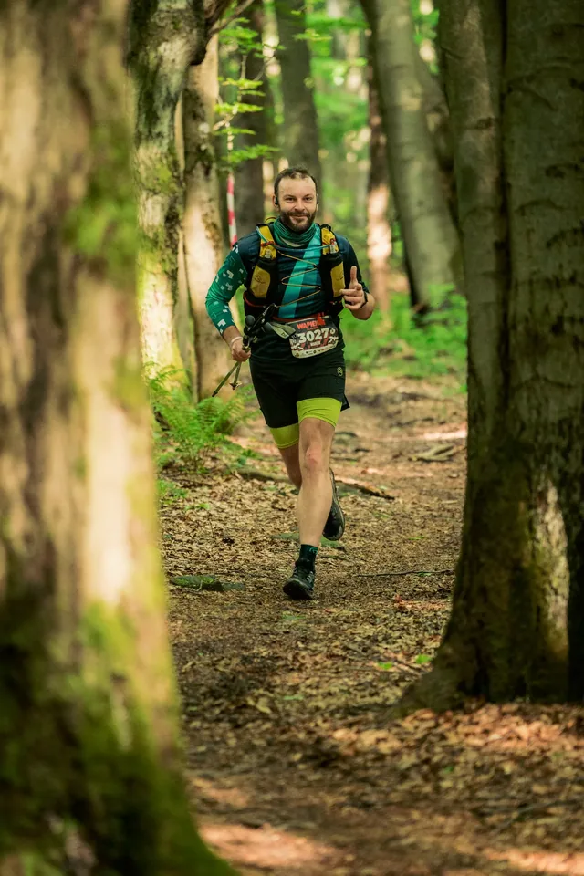 Runner between tree trunks in warm forest light.